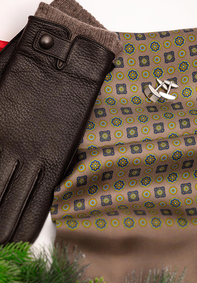 Close-Up von einem Seiden-Schal, Ansteckknöpfen und Leder-Handschuhen