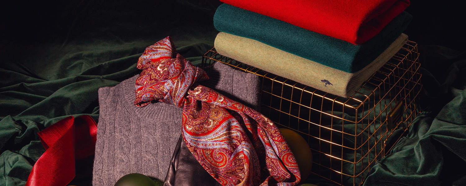 Zu sehen ist ein Stapel mit drei Pullovern. Hinzu kommen ein feiner Seidenschal und ein grober Strickpullover