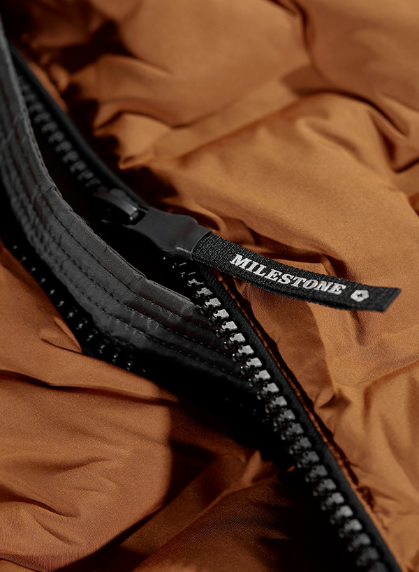 Eine Nahaufnahme eines Reißverschlusses an einer orangen Steppweste