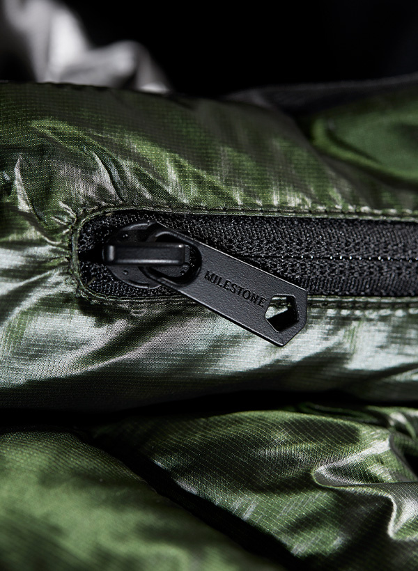 Nahaufnahme eines Reißverschlusses an einer dunkelgrünen Steppjacke