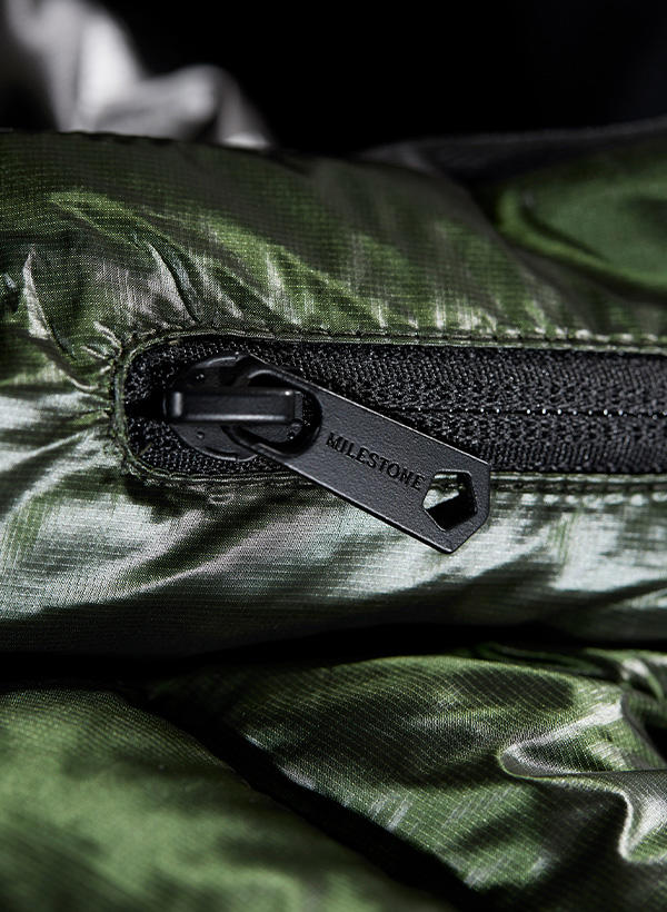 Nahaufnahme eines Reißverschlusses an einer dunkelgrünen Steppjacke