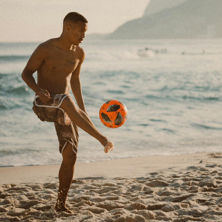 junger Mann macht Tricks mit einem Ball am Strand