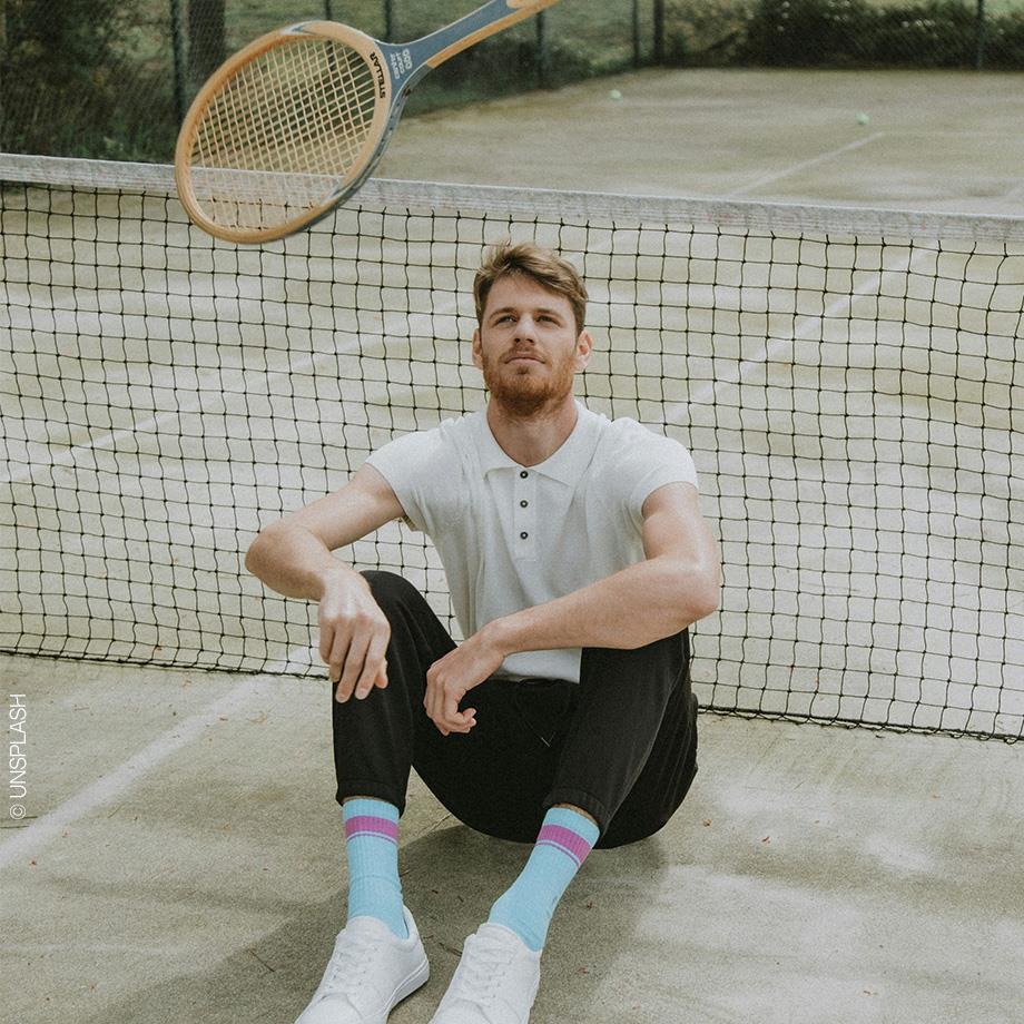 Ein Mann sitzt auf einem Tennisplatz, nachdem er eine Partie Tennis gespielt hat.