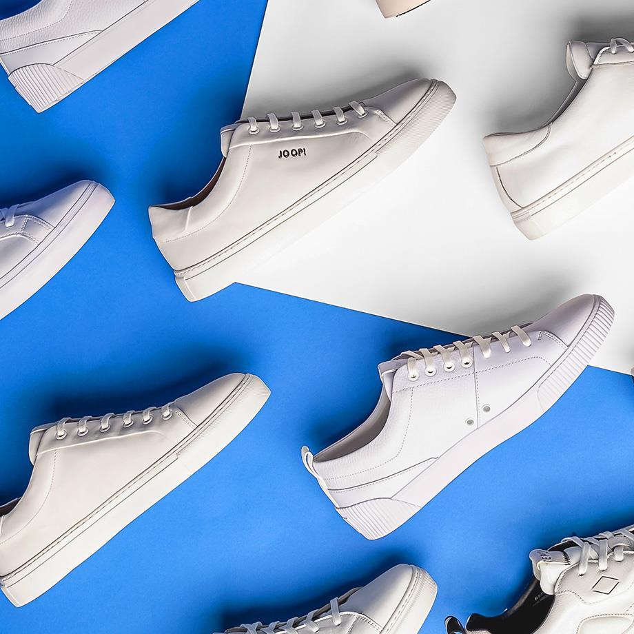 Eine Auswahl weißer Sneaker von Lacoste und Joop!