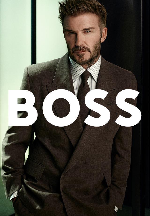 David Beckham in einem braunen Anzug, gestreiften Hemd und brauner Krawatte von Boss. 