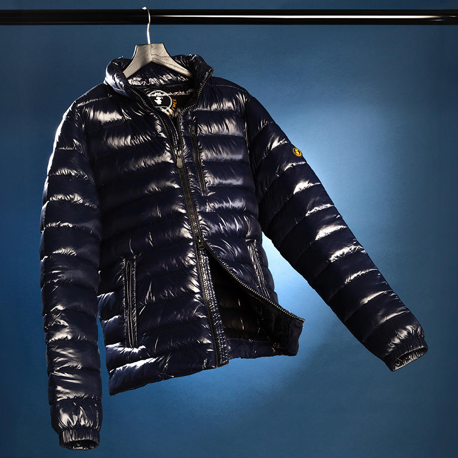 Ein Stillleben einer dunkelblauen Leichtstepp-Jacke vor blauem Hintergrund