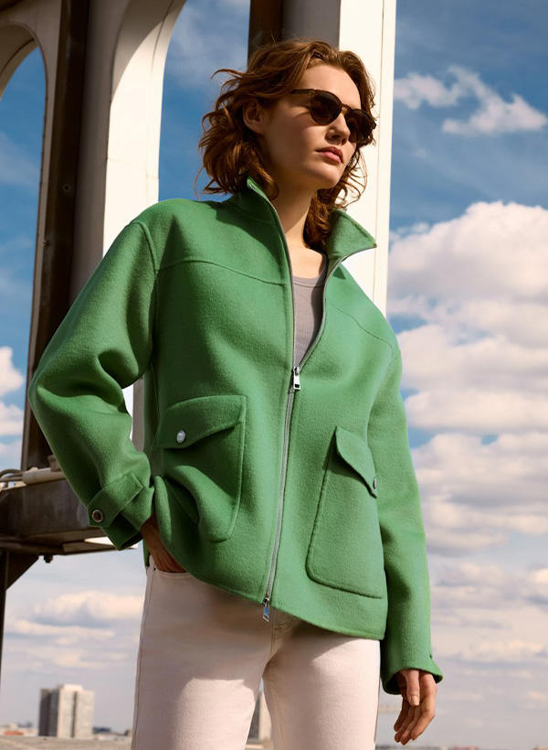 Eine Frau trägt eine grüne Wolljacke und eine Sonnenbrille