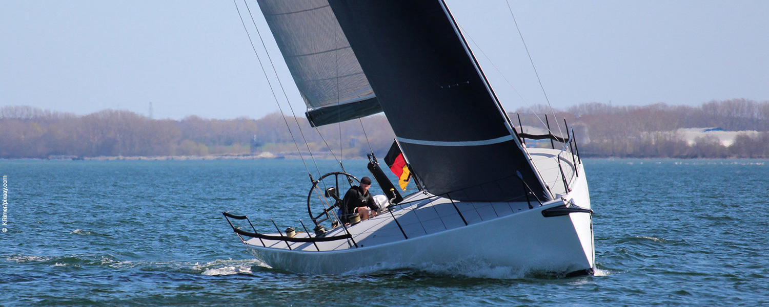 Ein Segler sitzt in einem Segelboot und segelt über das Wasser. 