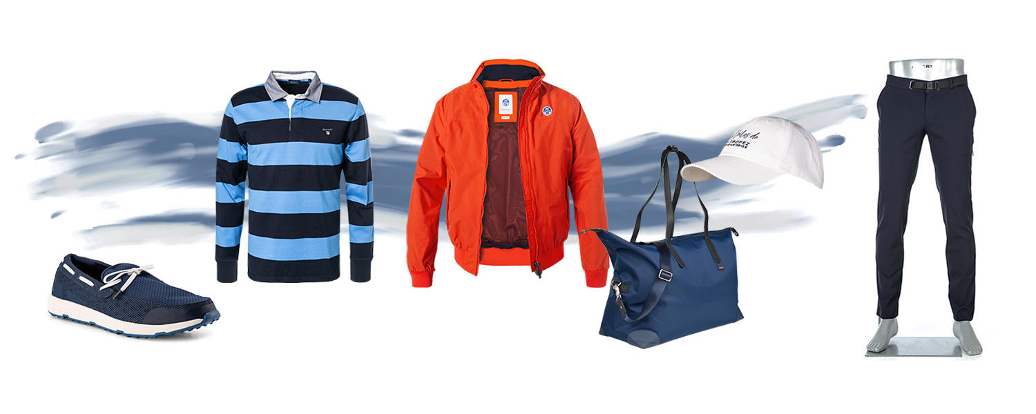 Zu sehen ist ein Segel-Look bestehend blauen Bootsschuhen, blau-weißem Rugby-Poloshirt, orangfarbener Jacke, blauer Tasche, weißer Cap und blauer Hose. 