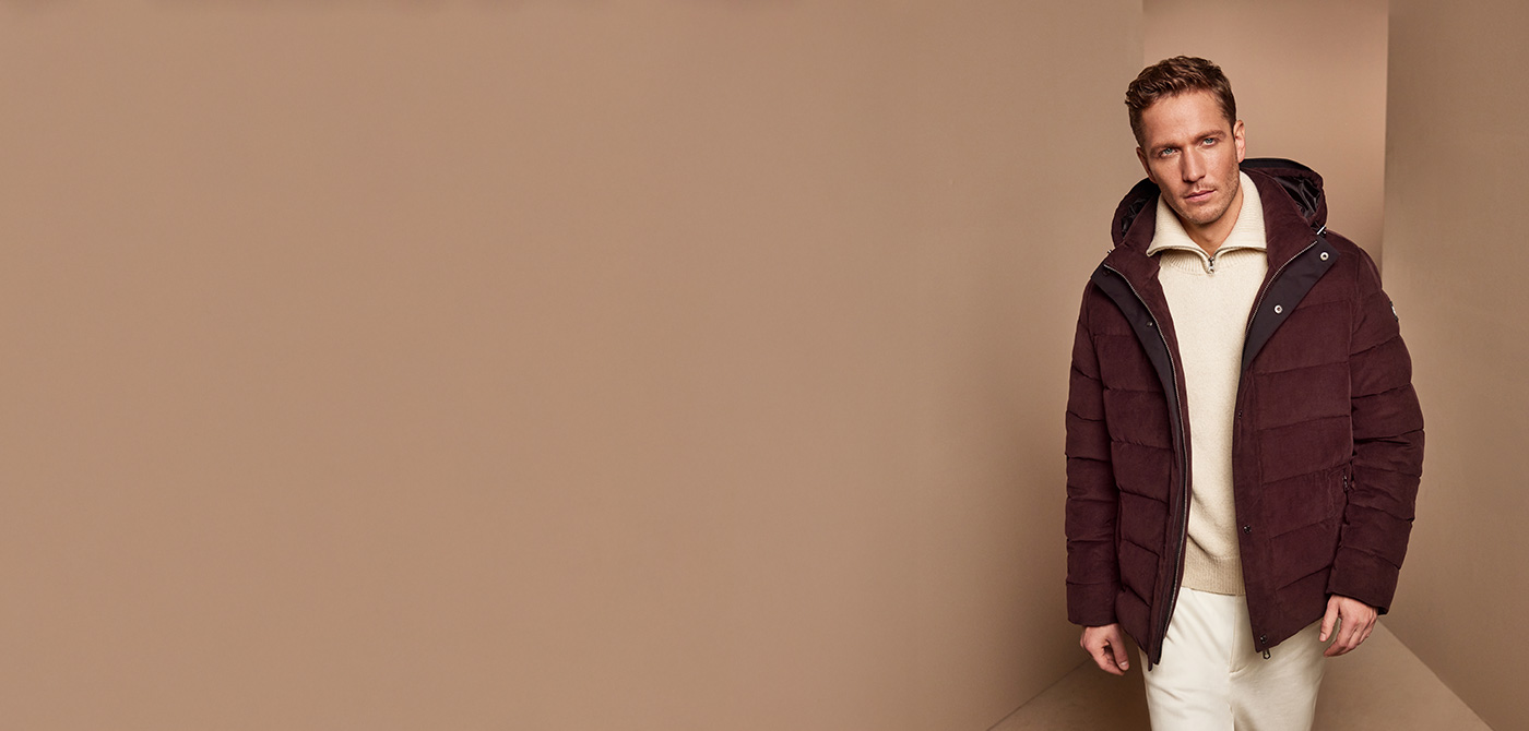 Ein Mann trägt eine burgunderfarbene Steppjacke
