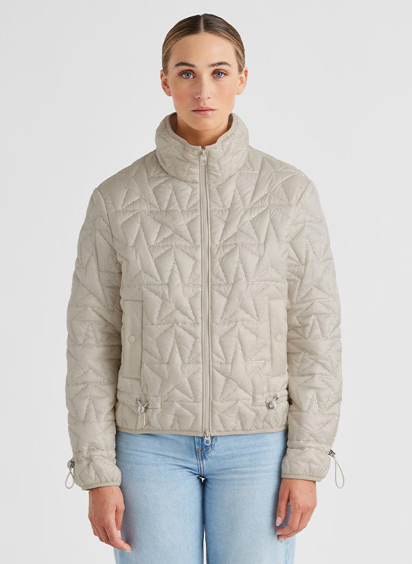 Beigefarbene Steppjacke mit geometrischem Muster, Reißverschluss, getragen über blauer Jeans