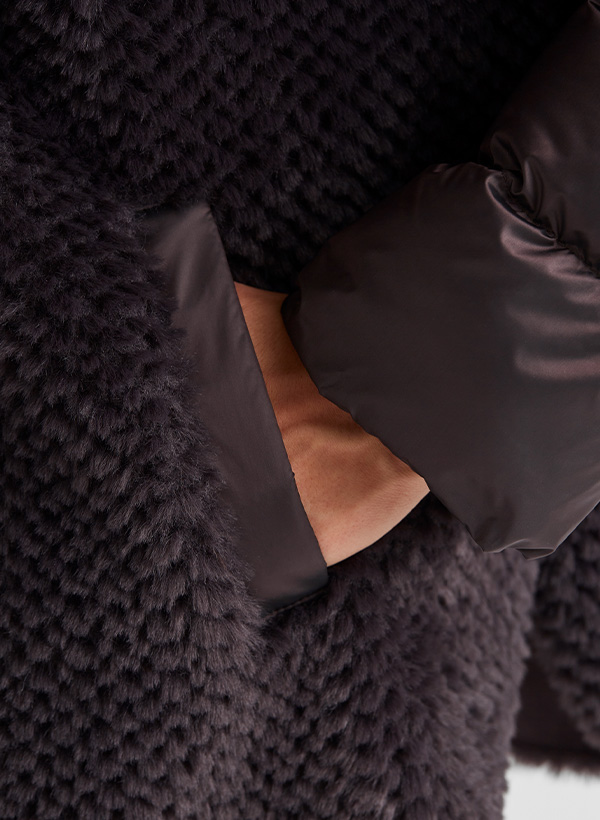 Dunkelbrauner Wollmantel mit gesteppter Ärmeltasche, elegant getragen