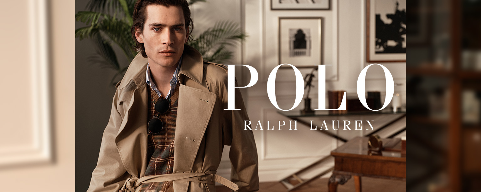 Polo Ralph Lauren Herren Trenchcoat kombiniert mit kariertem Pullover und Hemd, eleganter Look im Interieur.
