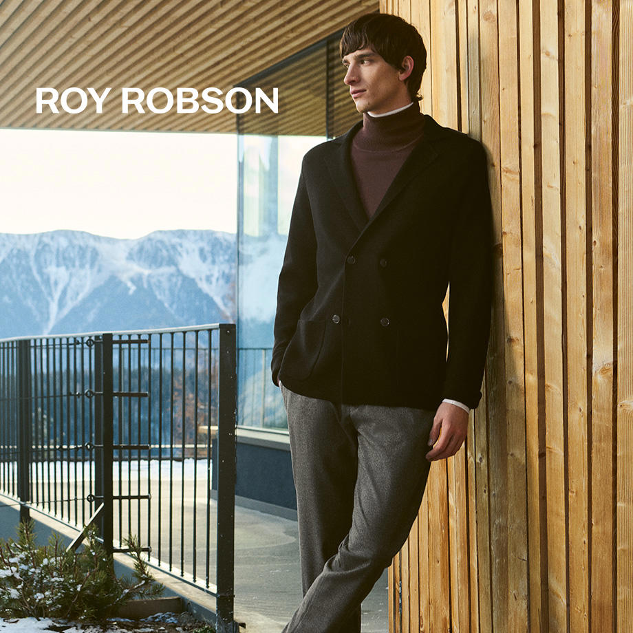 Roy Robson Herren Sakko in Schwarz mit braunem Rollkragenpullover, eleganter Look vor moderner Bergkulisse.