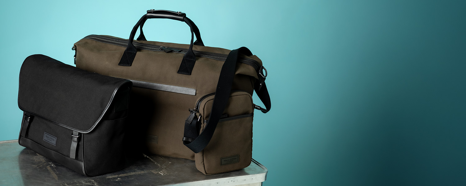 Schwarze Laptop-Tasche und olivgrüne Reisetasche, robustes Material, auf Tisch platziert