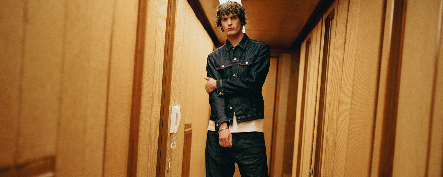 Mann in dunkelblauer Denim-Jeansjacke und dunkelblauer Jeans im Flur, casual Look