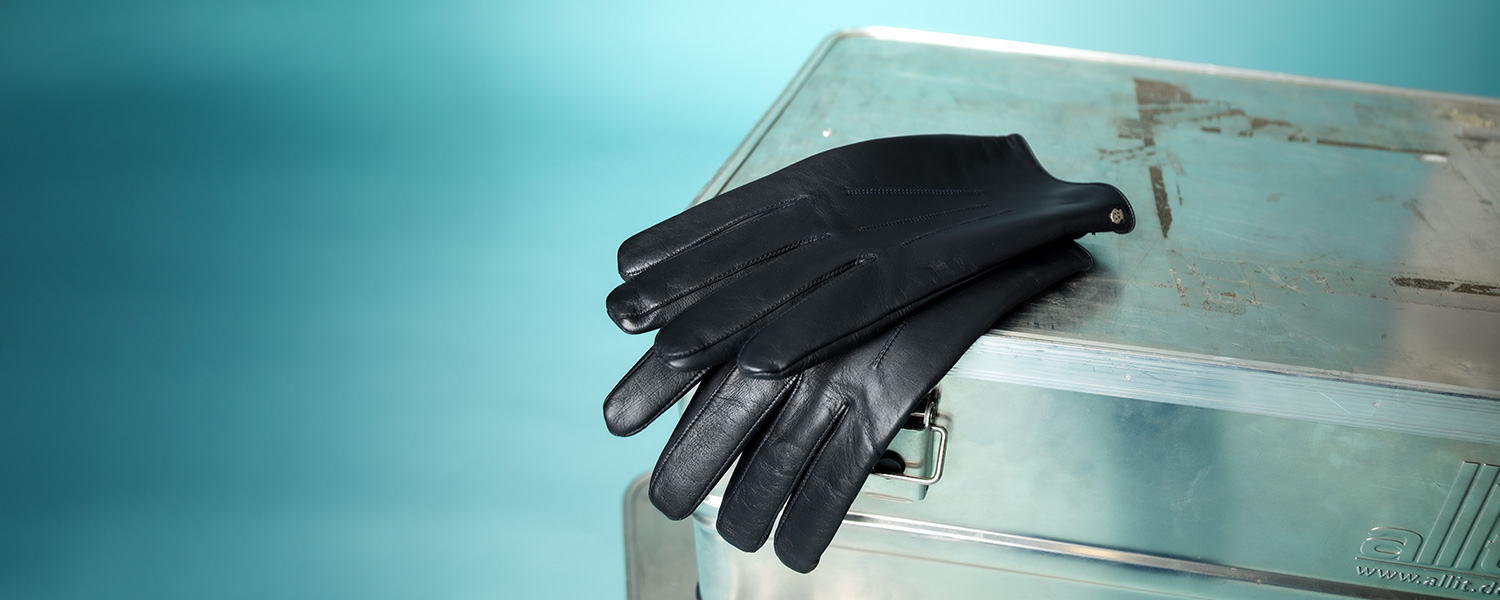 Schwarze Lederhandschuhe auf Metallkiste, elegant präsentiert