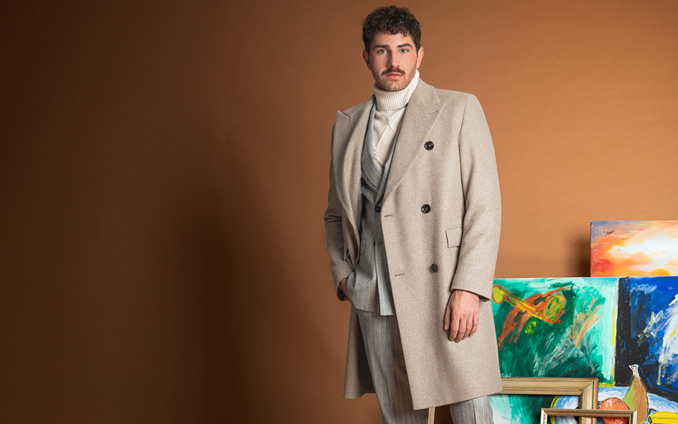 Hellbeiger Herrenmantel aus Wolle über Anzug und Rollkragenpullover getragen, elegant präsentiert