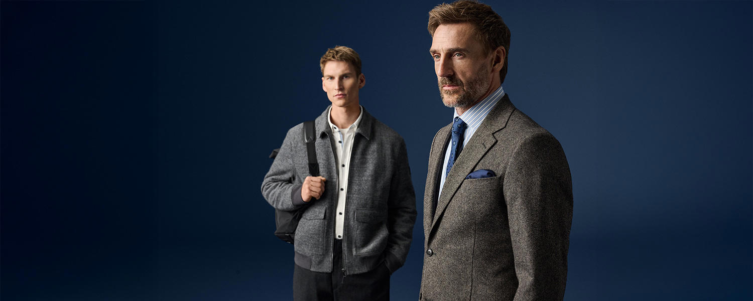 Grauer Tweed-Blazer mit blauem Einstecktuch und Hemd, neben Mann in grauer Jacke und Rucksack