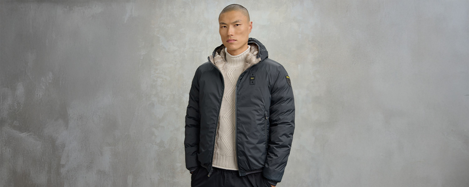 Mann in schwarzer Daunenjacke und beigem Strickpullover, lässig getragen