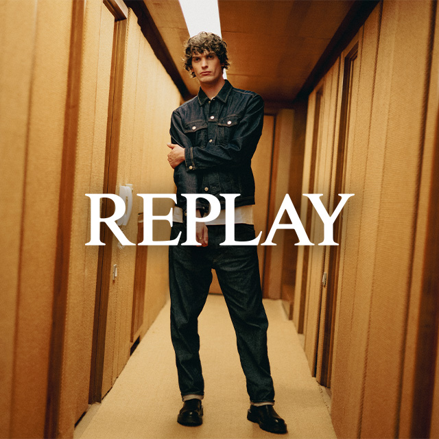 Mann in dunkler Jeansjacke und Jeanshose, lässig in Flur stehend