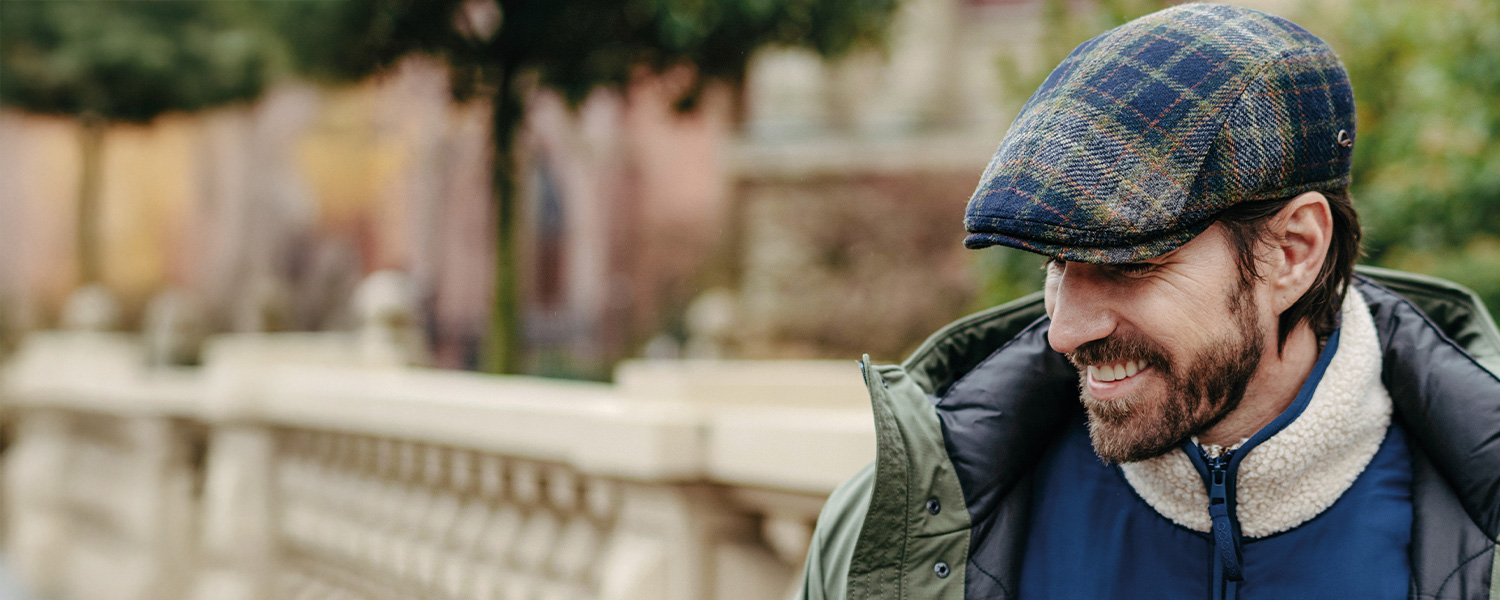 Mann mit karierter Schiebermütze und Outdoorjacke im Freien