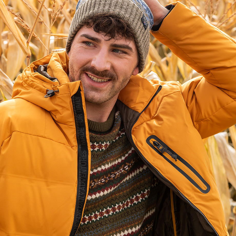 Mann in gelber Steppjacke mit Musterpullover im Freien