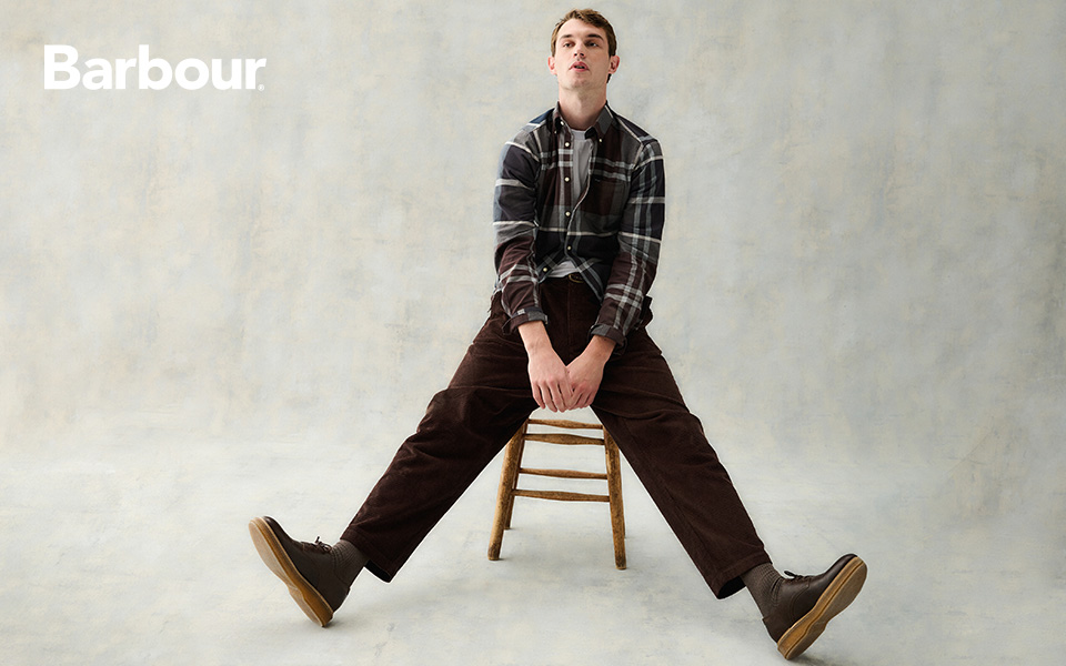 Mann in karierter Herbstjacke und brauner Cordhose auf Stuhl sitzend