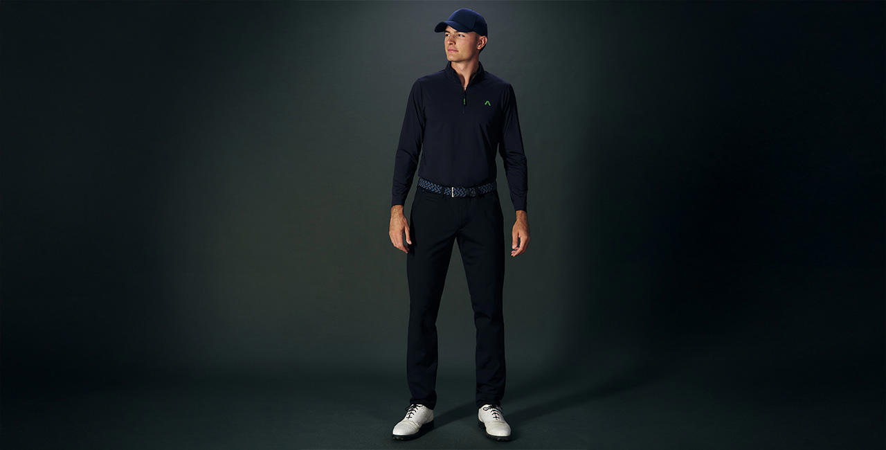 Mann in schwarzem Golf-Outfit mit Kappe und weißen Golfschuhen