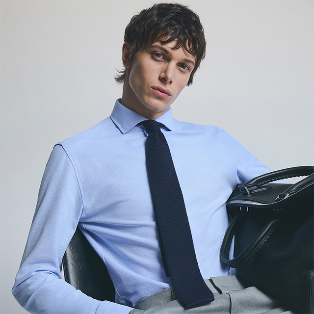 Mann in hellblauem Business-Hemd mit dunkelblauer Krawatte, elegant im Büro