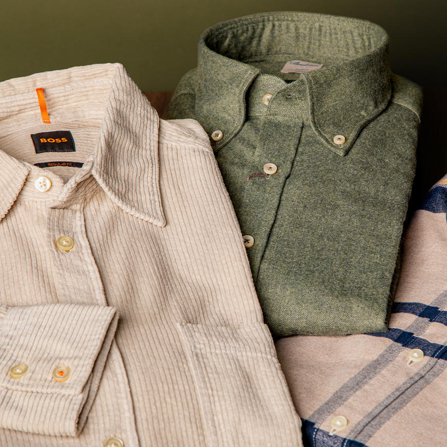 Beigefarbenes Cordhemd, grünes Button-Down-Hemd, kariertes Hemd im Hintergrund, gefaltet präsentiert.