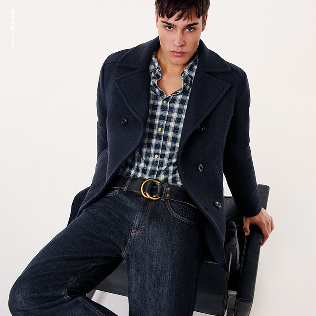 Dunkelblauer Wollmantel über kariertem Hemd und Jeans, smarter Casual-Look mit goldener Gürtelschnalle.