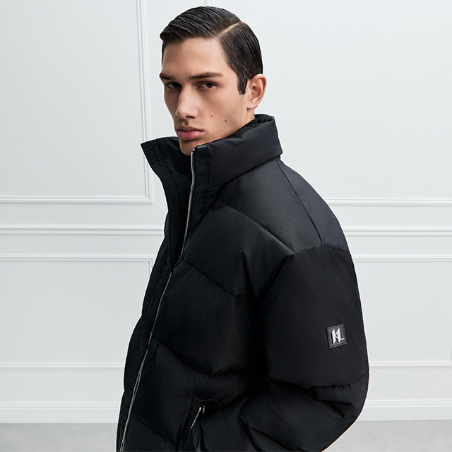 Schwarze Daunenjacke mit hohem Kragen und Logo-Detail, sportlich-eleganter Winter-Look.