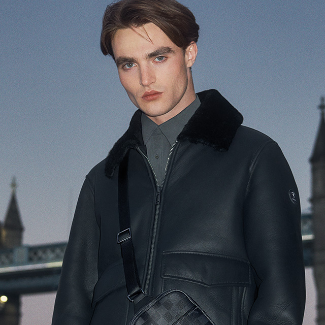 Schwarze Lederjacke mit Fellkragen, kombiniert mit grauem Hemd, urbaner Winter-Style.