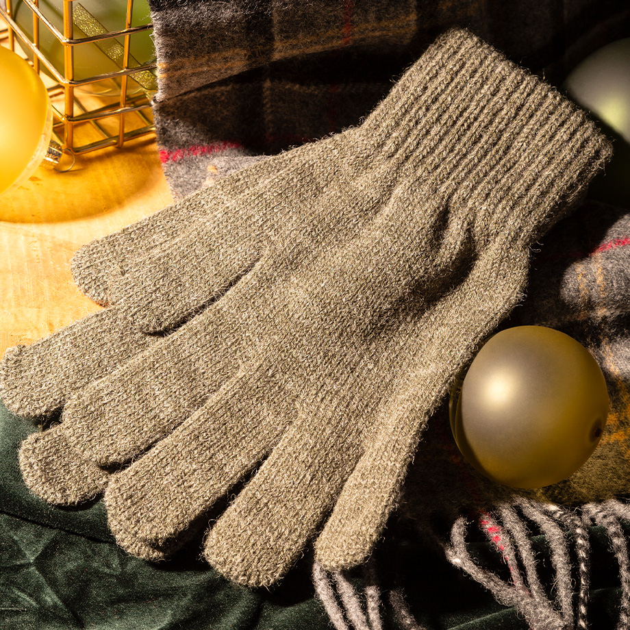 Beigefarbene Strickhandschuhe aus Wolle auf kariertem Schal, dezent drapiert