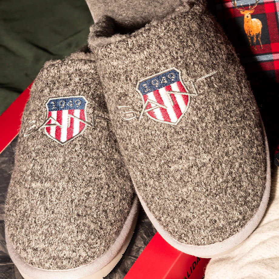 Graue Filzhausschuhe mit gesticktem Wappen, gemütlich präsentiert