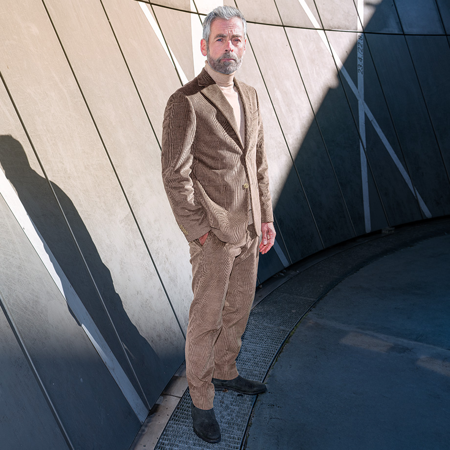 Mann in braunem Cordanzug mit Rollkragenpullover, elegant präsentiert