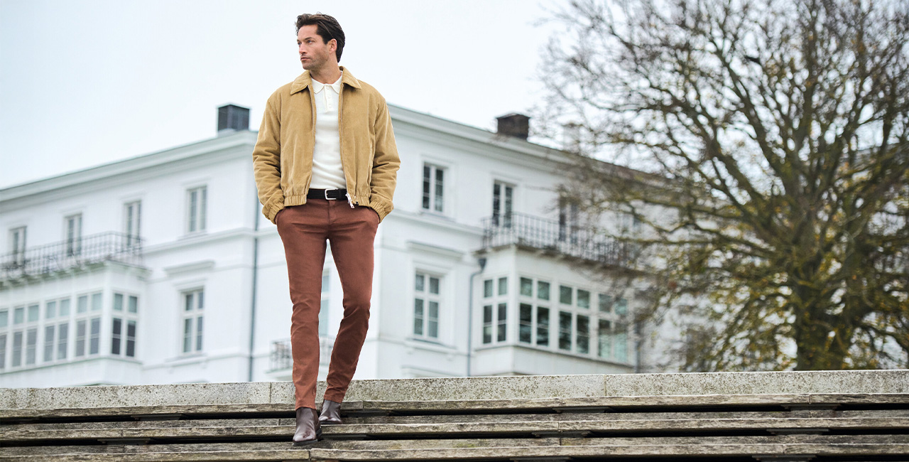 Mann in beiger Wildlederjacke und brauner Hose, lässig im Freien