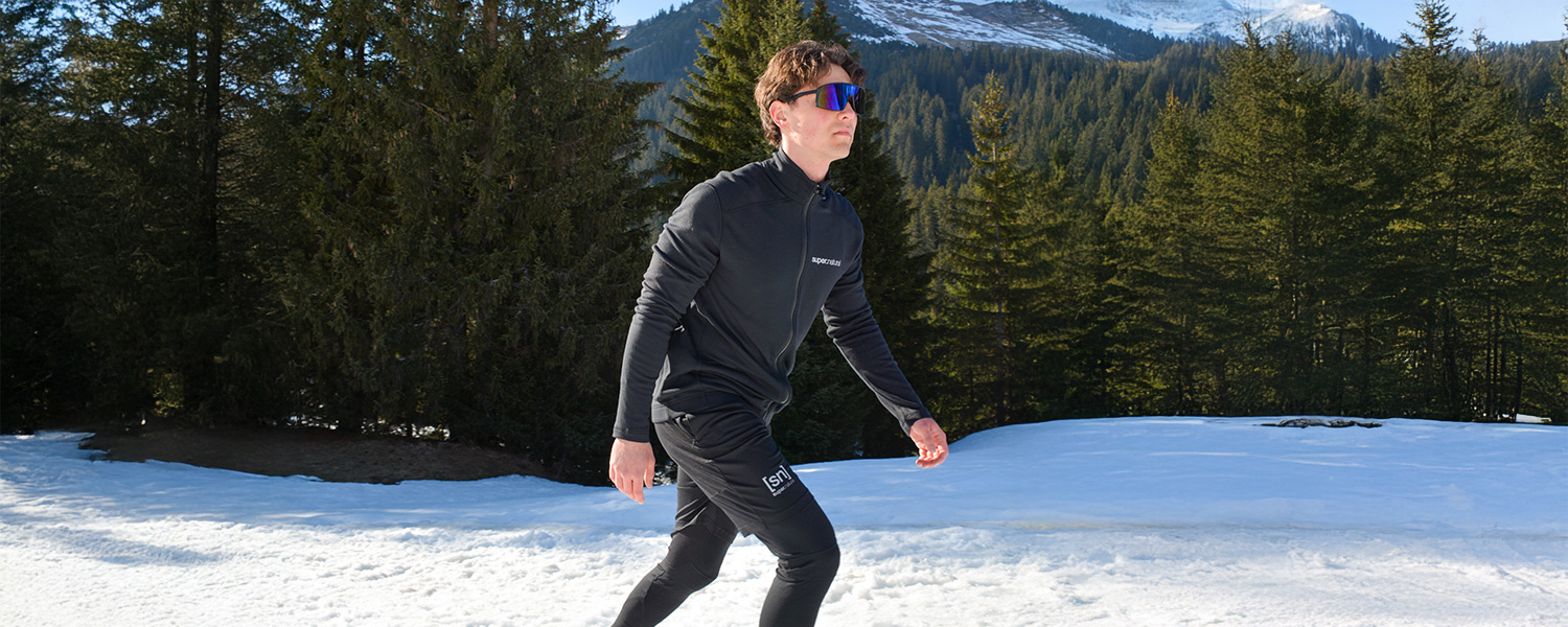 Mann in schwarzer Funktionsjacke und -hose, sportlich beim Joggen im Schnee