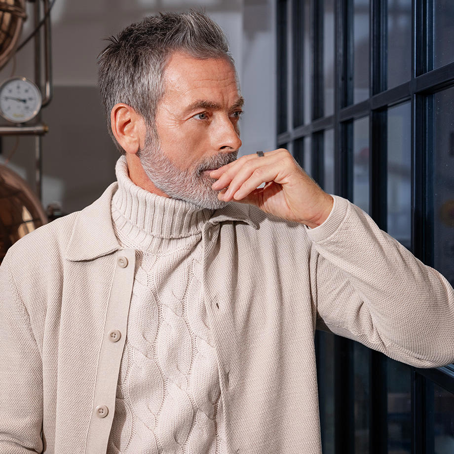 Hellgrauer Strickpullover mit Zopfmuster und Rollkragen, getragen unter beiger Jacke