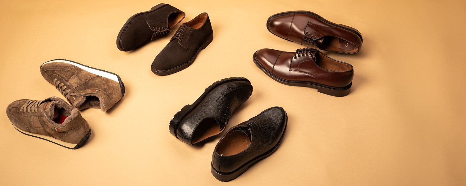 Verschiedene Herrenschuhe: braune und schwarze Lederschnürschuhe sowie braune Wildleder-Sneaker, elegant präsentiert