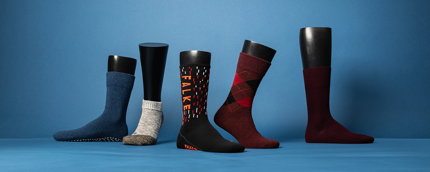 Verschiedene Herren-Socken: Blaue, graue, schwarz-rote, rot-karierte und burgunderrote Socken auf schwarzem Aufsteller