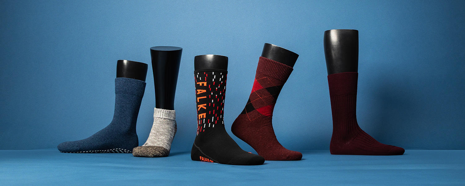 Verschiedene Herren-Socken: Blaue, graue, schwarz-rote, rot-karierte und burgunderrote Socken auf schwarzem Aufsteller