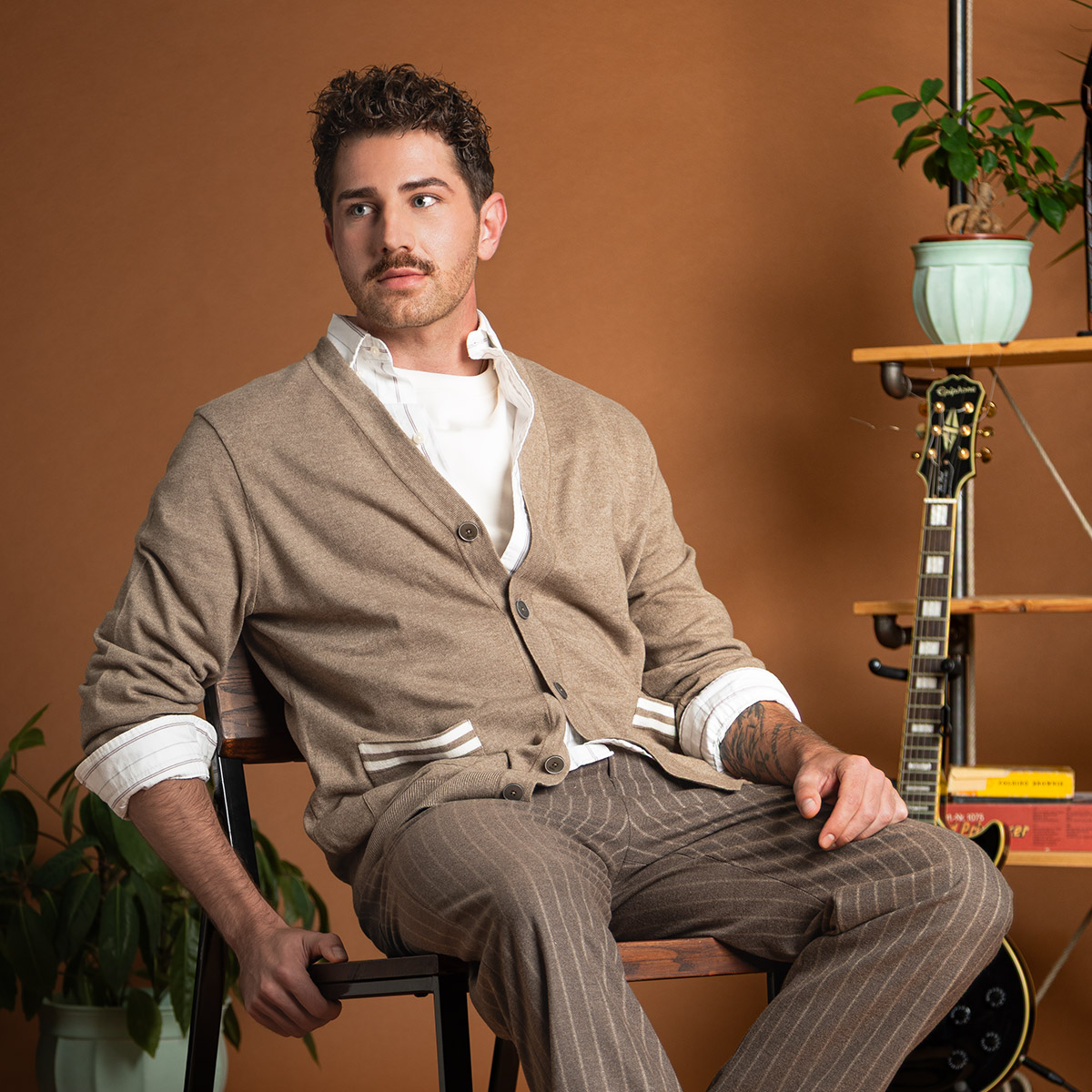 Knit-Cardigan in Beige, über weißem Hemd, getragen von Mann, braun gestreifte Anzughose