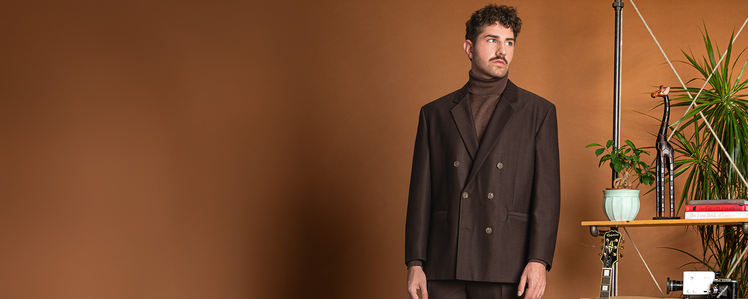 Mann in braunem Doppelreiher-Sakko und Rollkragenpullover, elegant präsentiert im Büro