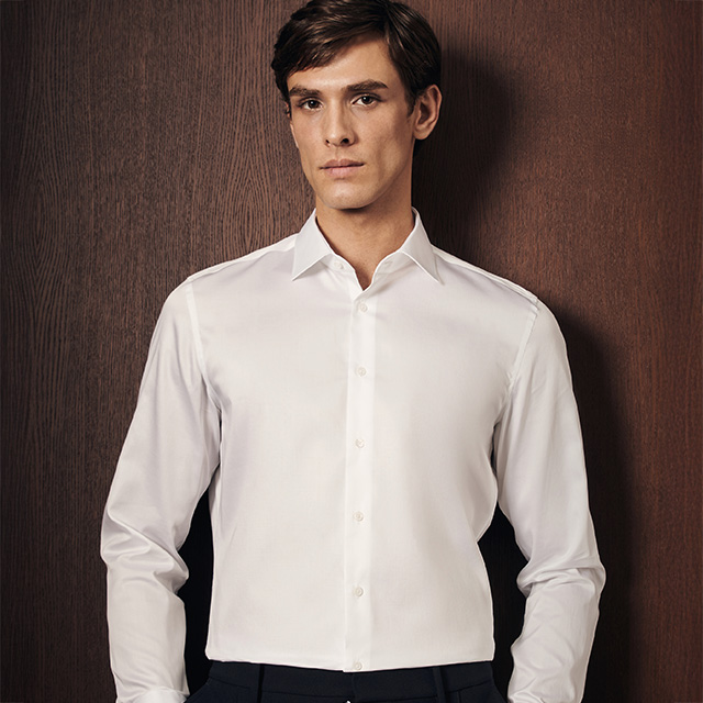 Weißes Business-Hemd aus Baumwolle, klassischer Schnitt, von Mann vor Holzwand getragen