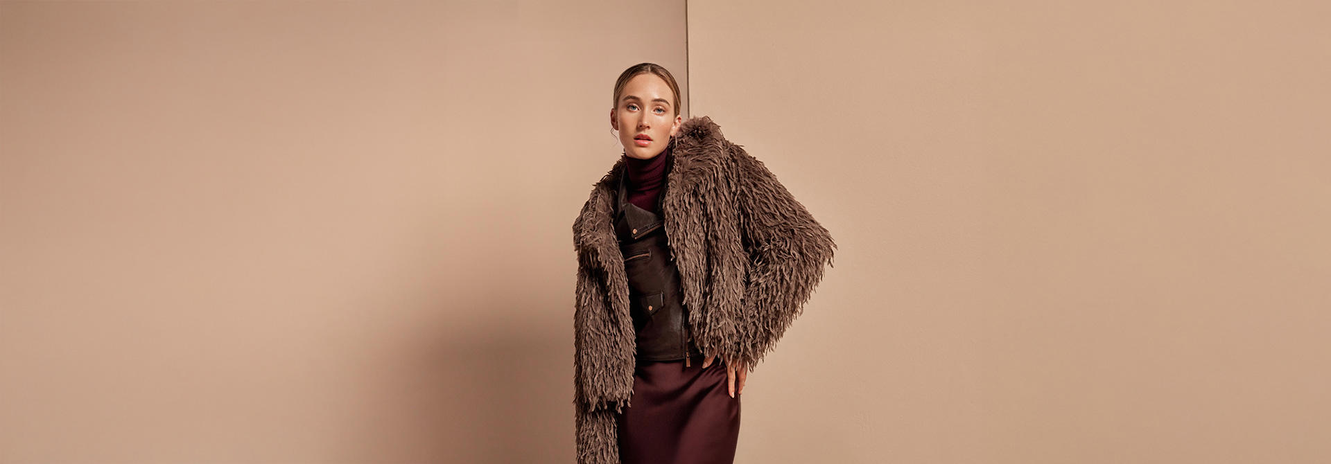 Braune Fake-Fur-Jacke über Satinrock und Rollkragenpullover, eleganter Look mit Retro-Charme.