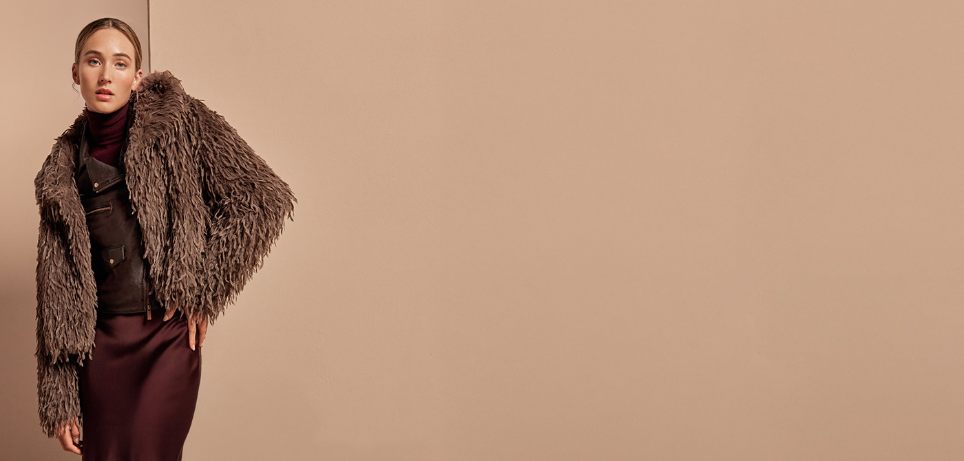 Braune Fake-Fur-Jacke über Satinrock und Rollkragenpullover, eleganter Look mit Retro-Charme.