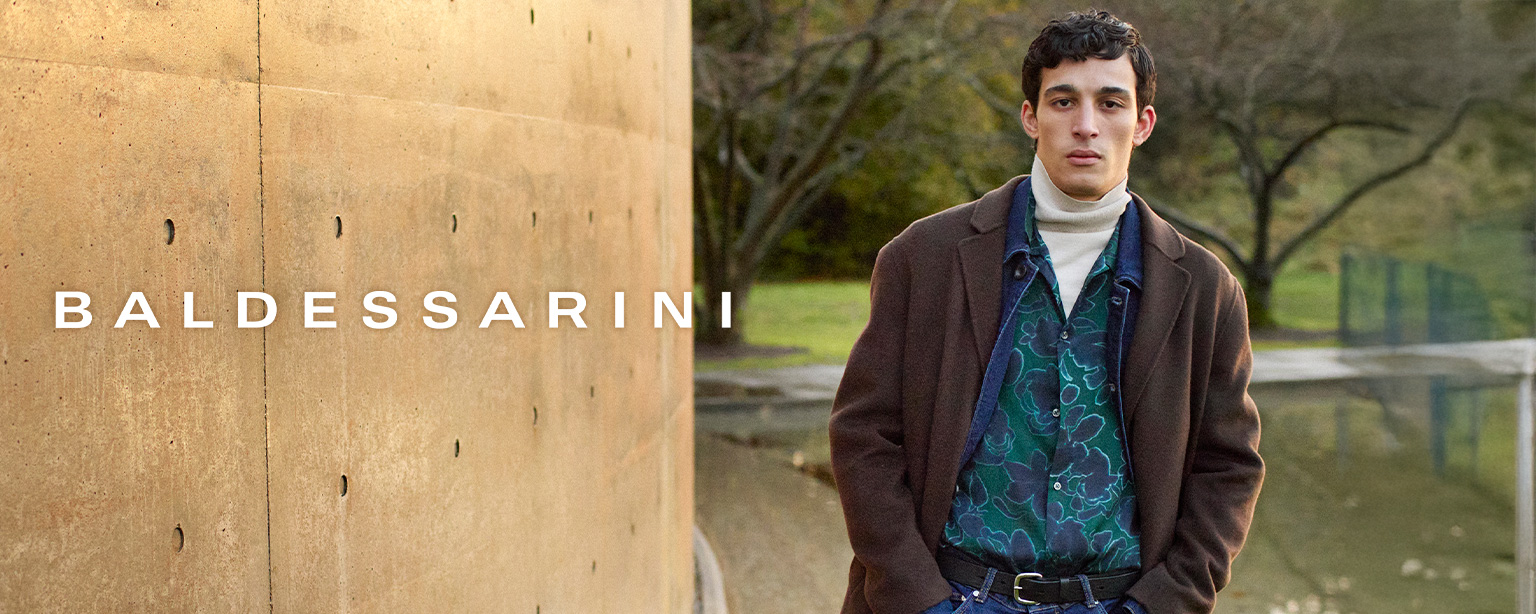 Mann in braunem Mantel, gemustertes Hemd in Grün und Rollkragenpullover im Freien