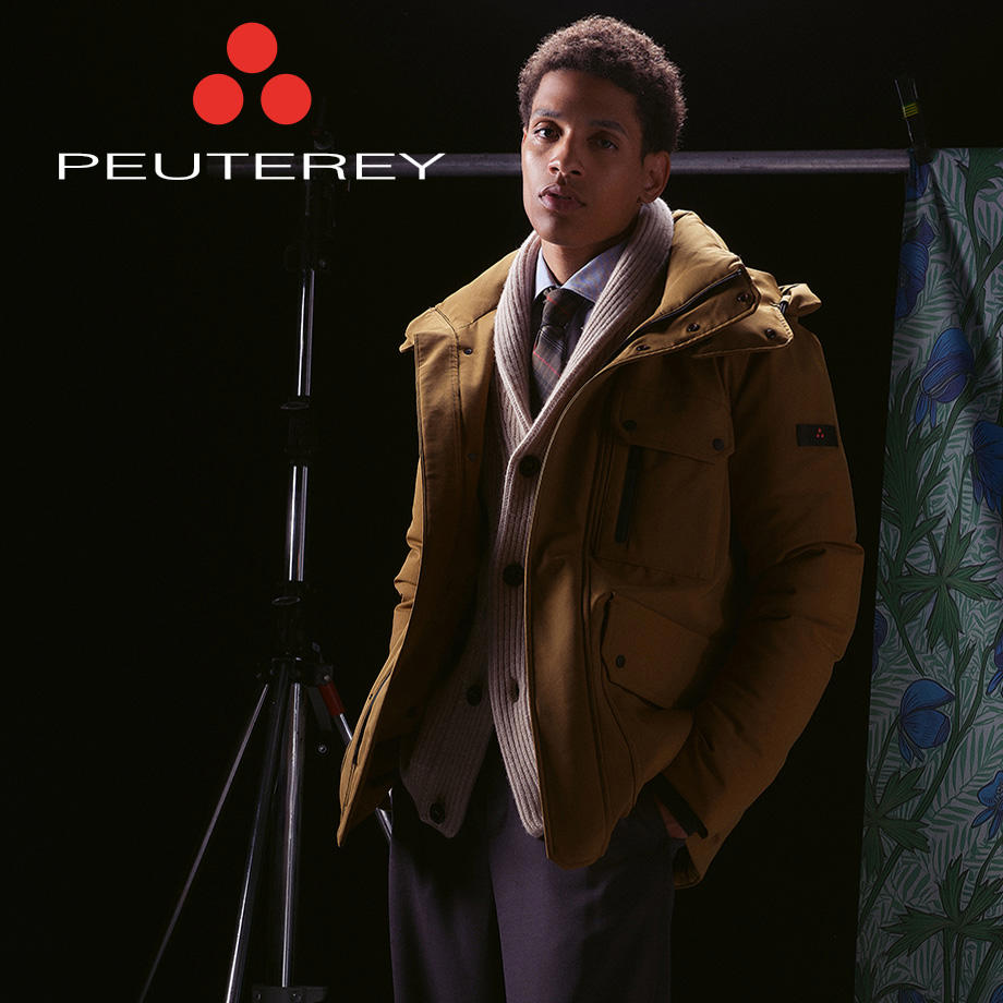 Mann in brauner Outdoor-Jacke mit weißem Strickpullover und Hemd, stehend